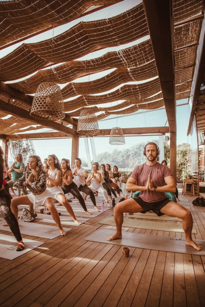 A diverse group practicing yoga together in a sunlit outdoor setting.