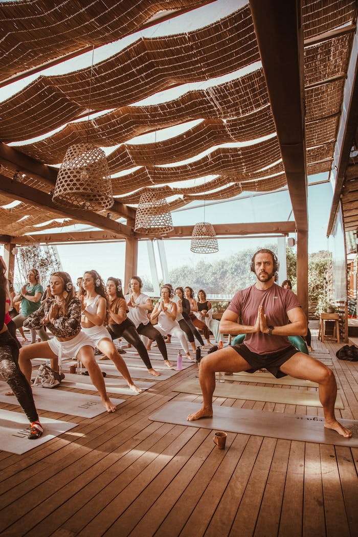 A diverse group practicing yoga together in a sunlit outdoor setting.