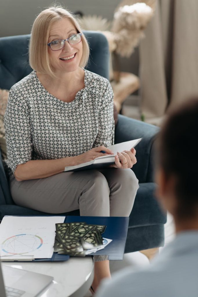 Smiling woman in a patterned blouse discussing horoscopes indoors.